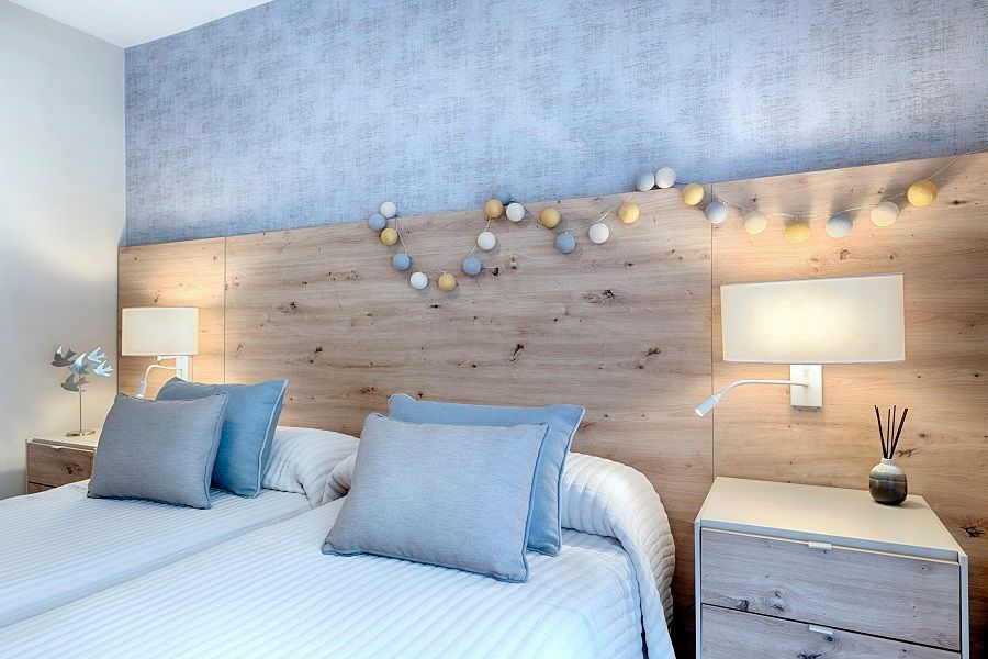 Un dormitorio con dos camas, dos mesitas de noche y un cabecero de madera.