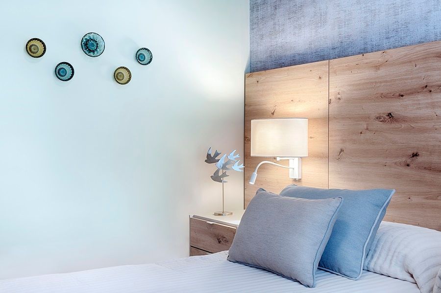 Un dormitorio con cama, mesita de noche, lámpara y cabecero de madera.