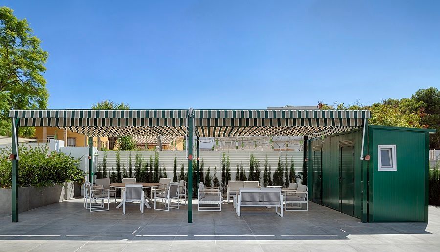 Un área de patio con mesas y sillas bajo un toldo a rayas.