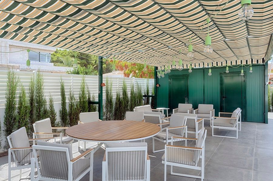 Un patio con mesas y sillas bajo un dosel.