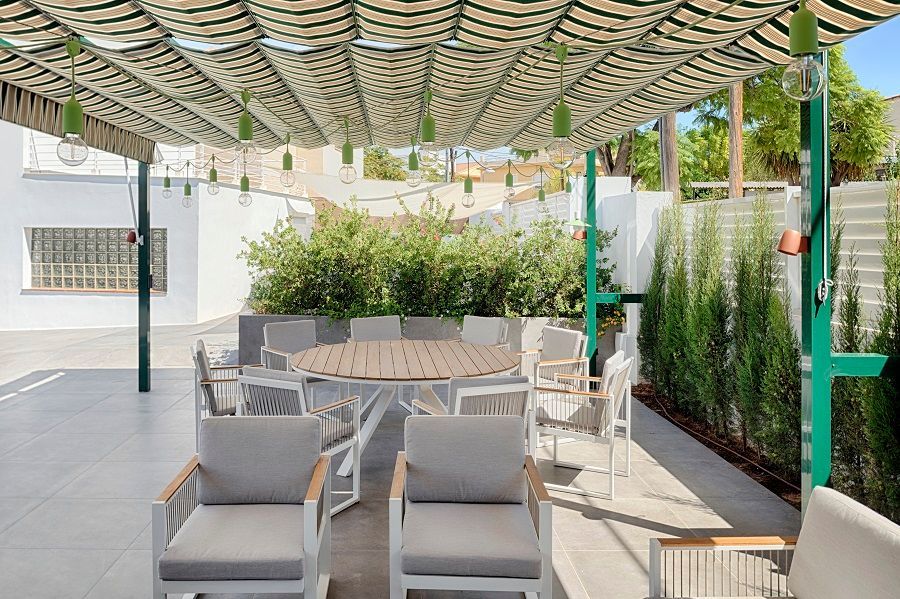 Un patio con una mesa y sillas bajo un dosel.