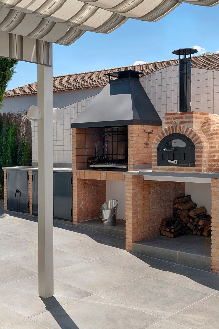 Un horno de ladrillos está situado bajo un dosel en un patio.