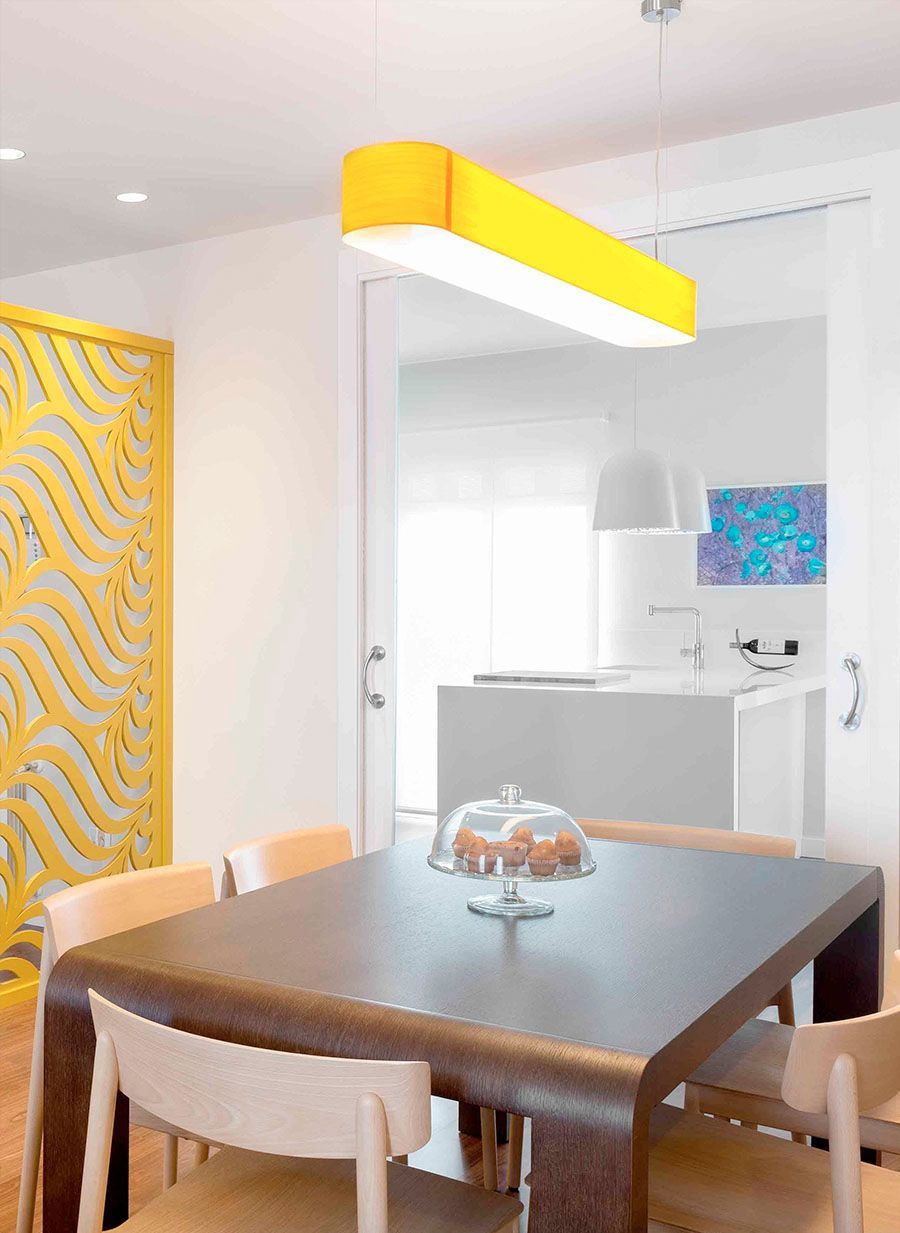 Una mesa de comedor con una luz amarilla colgando del techo.