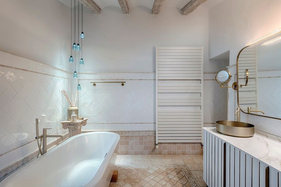 Un baño con bañera, lavabo, espejo y toallero.