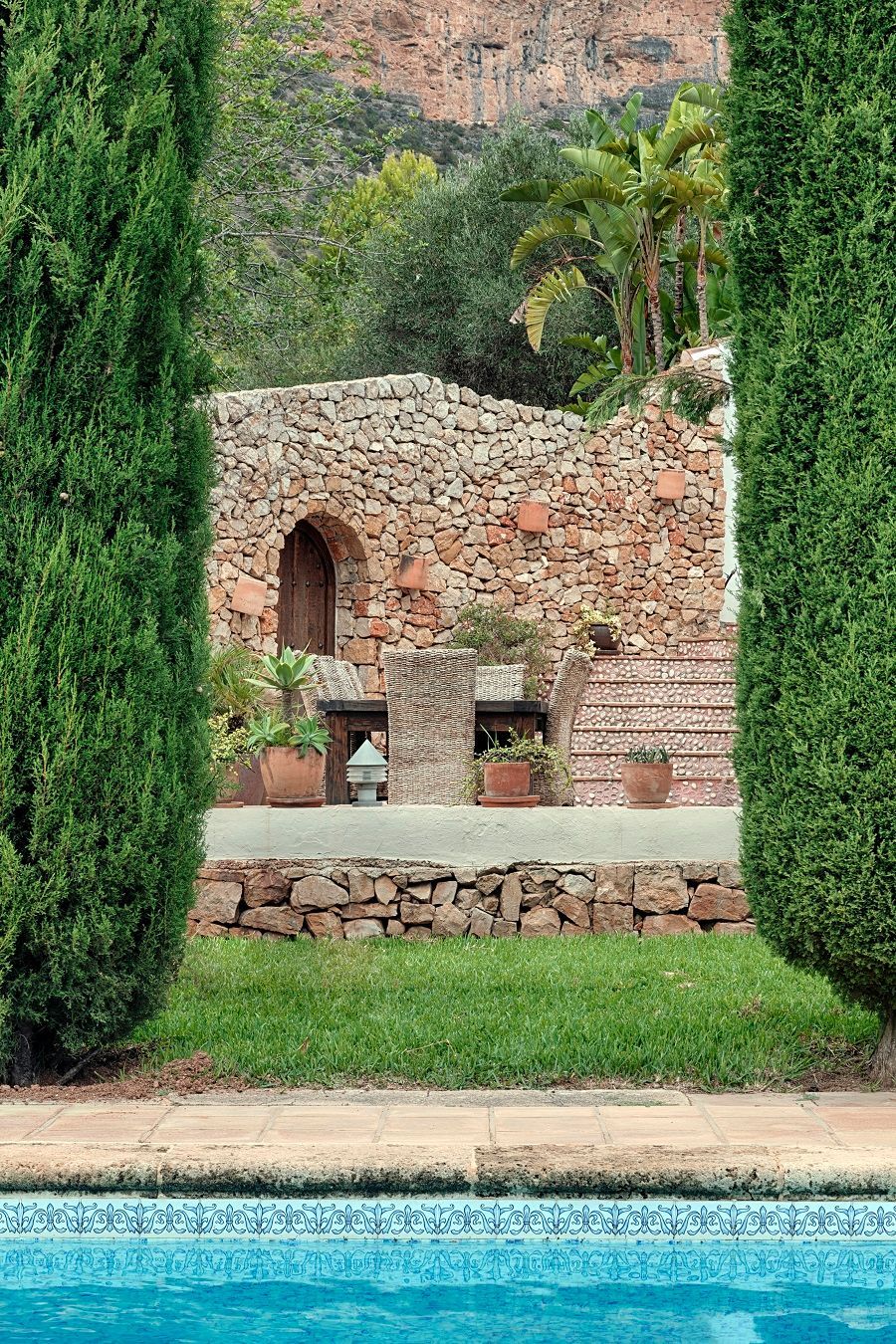Una piscina rodeada de árboles y un muro de piedra.
