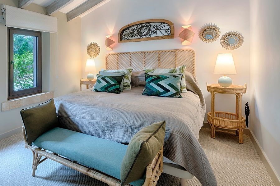 Un dormitorio con una cama, un banco, lámparas y una ventana.