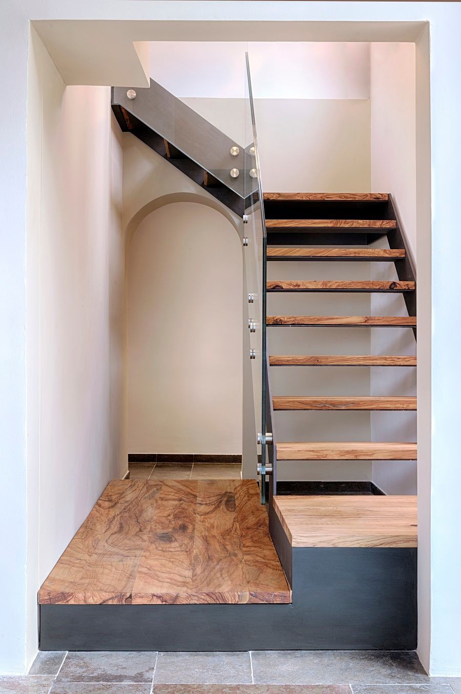 Una escalera con escalones de madera y barandilla de cristal en una habitación.