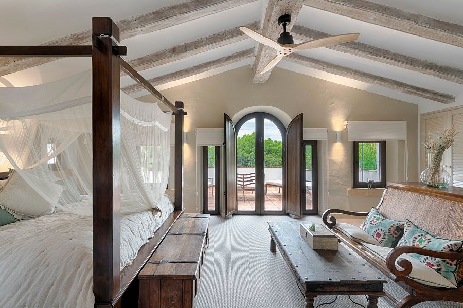 Un dormitorio con una cama con dosel, un sofá, una mesa de café y un ventilador de techo.