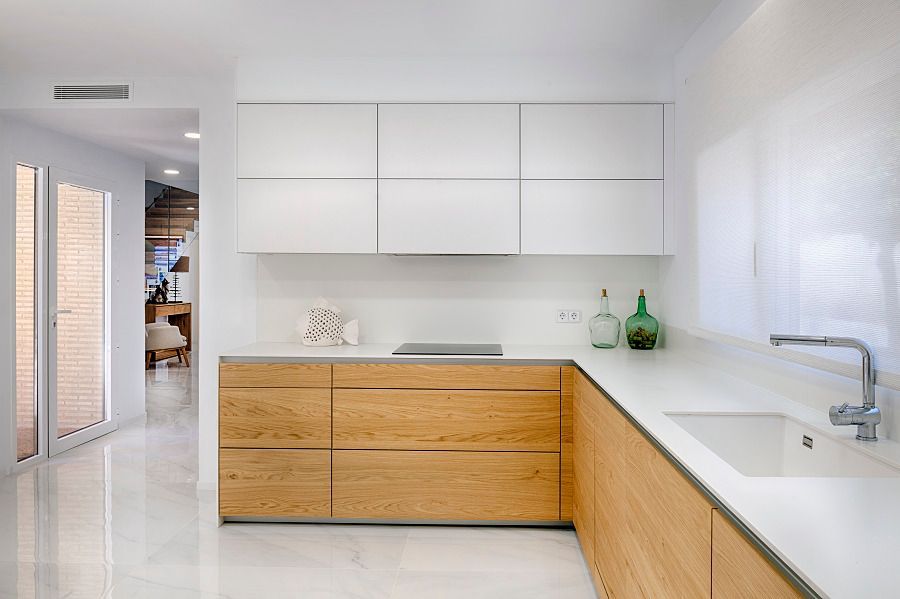 Una cocina con gabinetes de madera y encimeras blancas.
