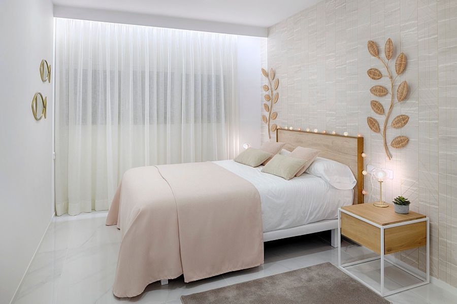 Un dormitorio con una cama, mesita de noche y cortinas.