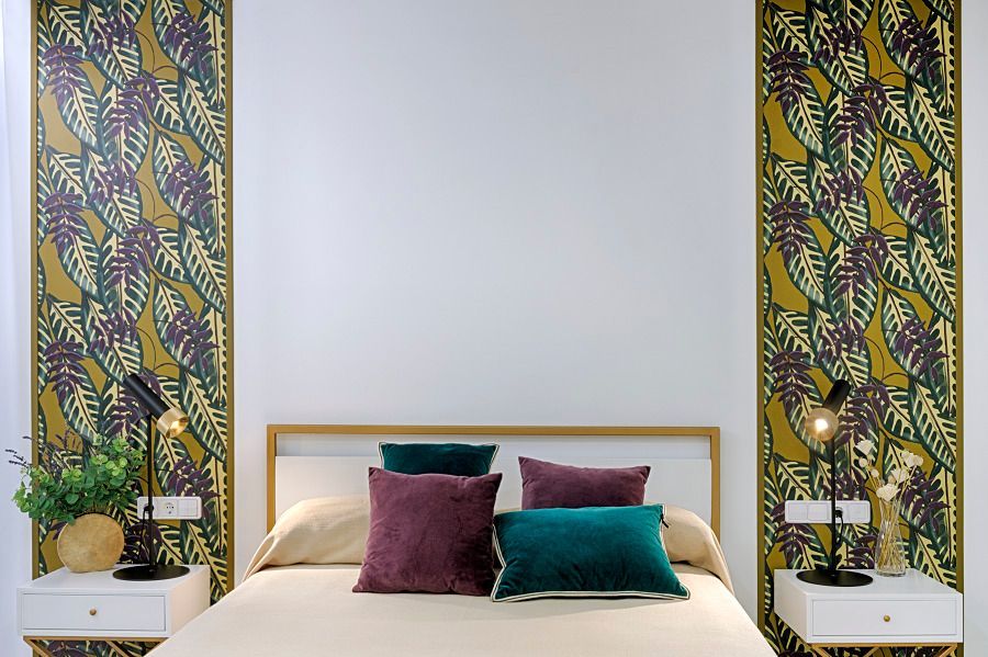 Un dormitorio con una cama y dos mesitas de noche con almohadas moradas y verdes.