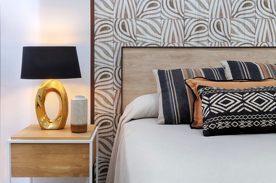 Un dormitorio con cama, mesita de noche y lámpara.