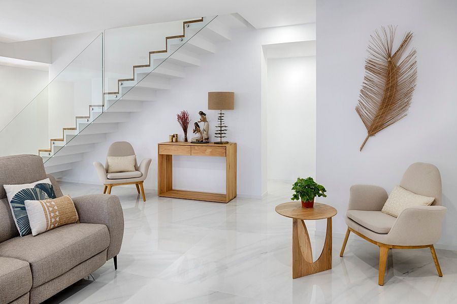 Una sala de estar con un sofá, sillas, una mesa y una escalera.