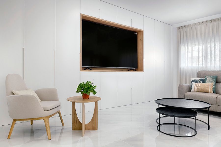 Una sala de estar con sofá, silla, mesa y televisión.