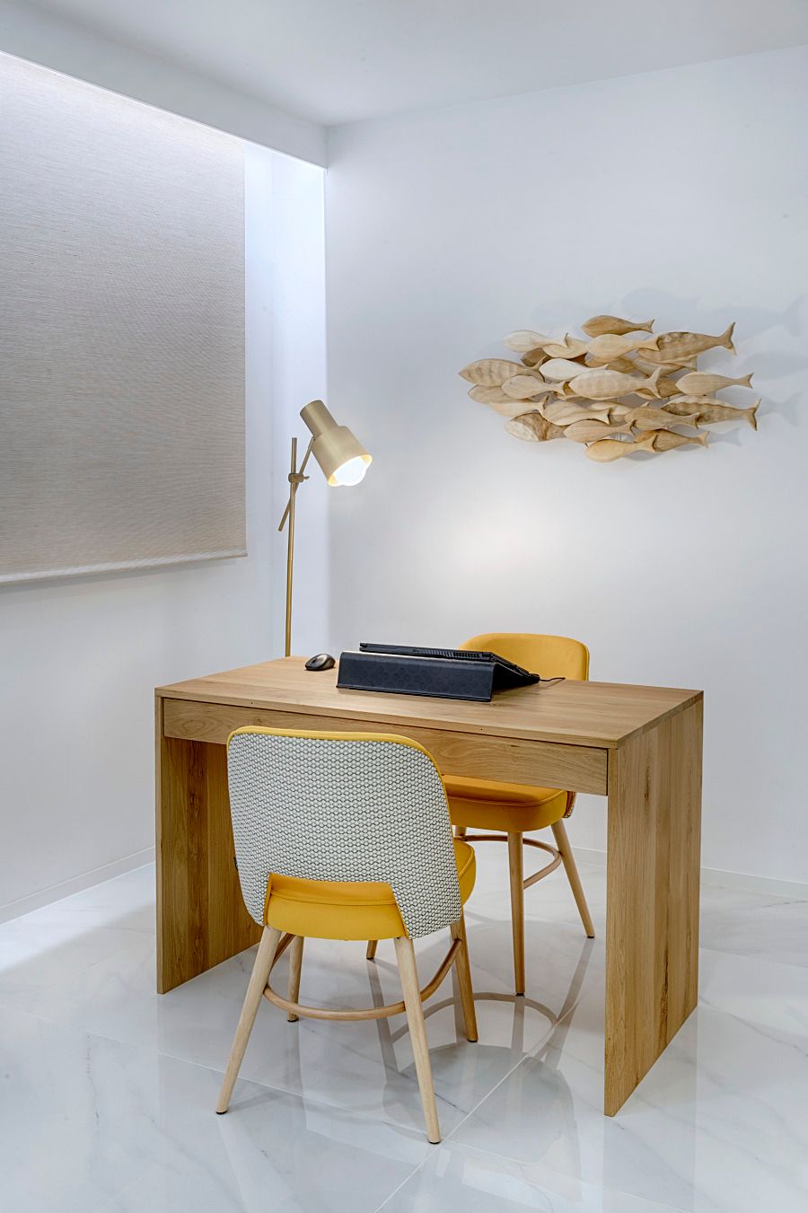 Un escritorio de madera con dos sillas amarillas y una lámpara en una habitación.