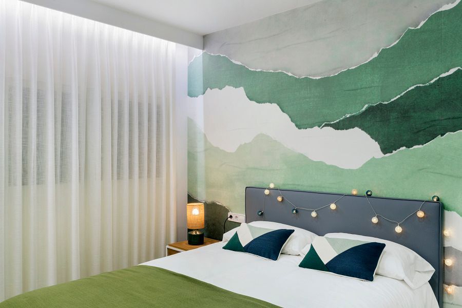 Un dormitorio con una cama y un mural de pared verde.