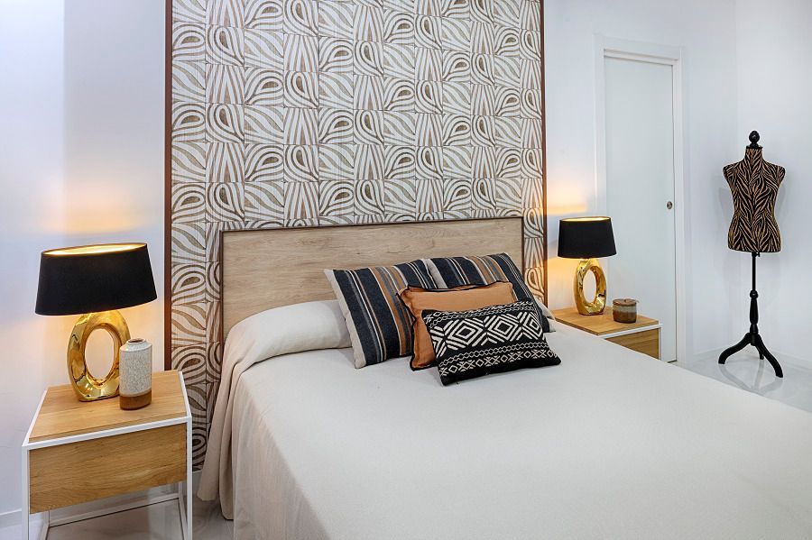 Un dormitorio con una cama, mesitas de noche, lámparas y un maniquí.