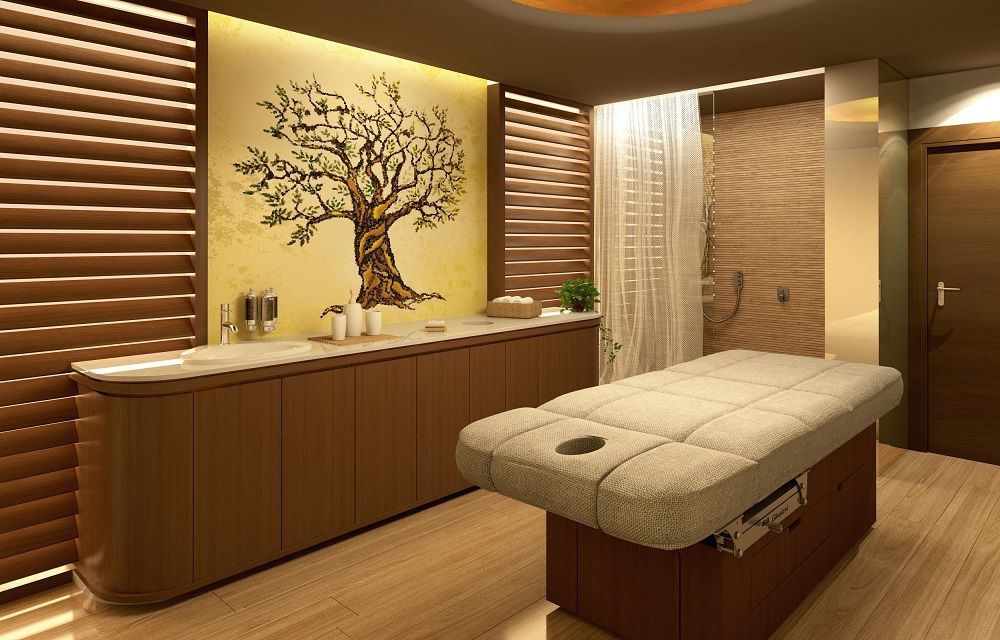 Una mesa de masajes en una habitación con un árbol en la pared.