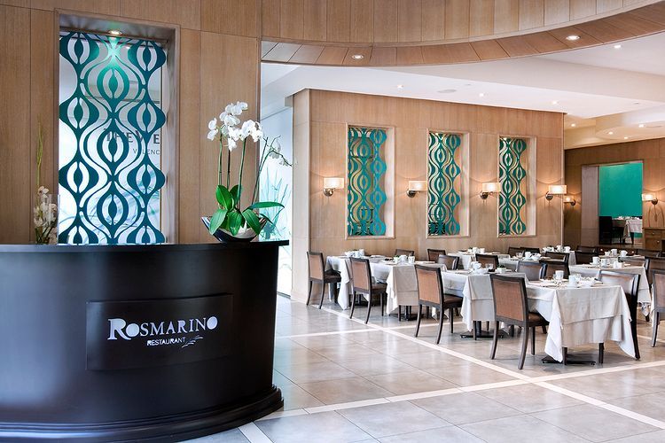 Un restaurante con mesas y sillas y un mostrador que dice Rosmarino.