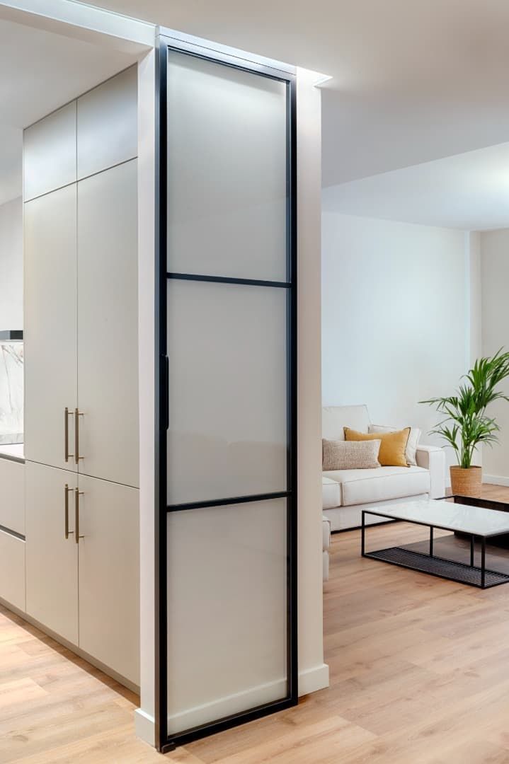 Salón moderno de planta abierta con un mueble separador blanco y un sofá al fondo.