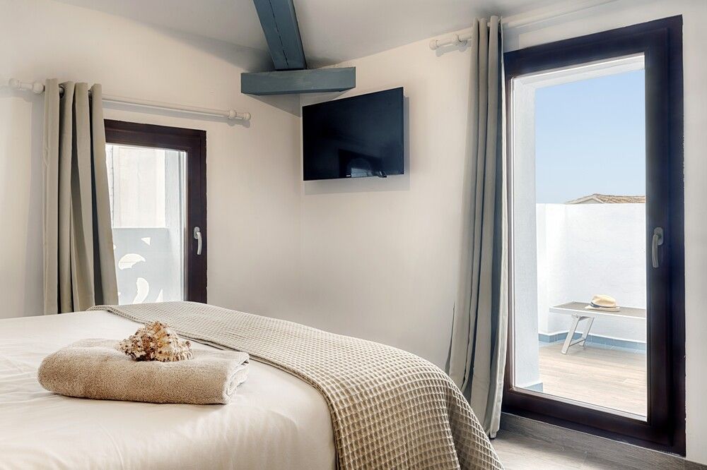 Un dormitorio con cama, televisión y puertas corredizas de vidrio.