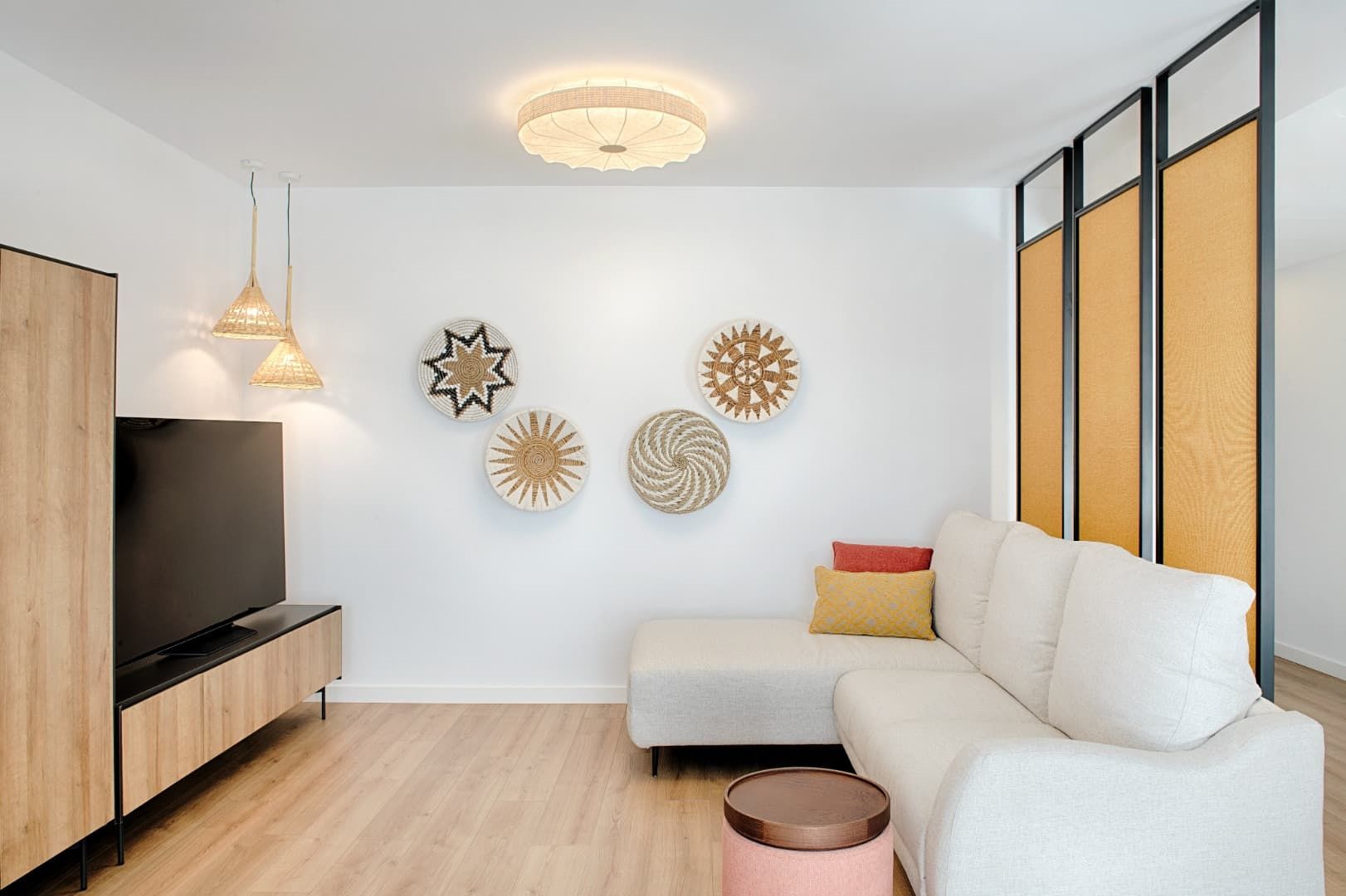 Sala de estar moderna con sofá blanco, televisor, suelo de madera, decoración de pared y mampara de vidrio esmerilado.