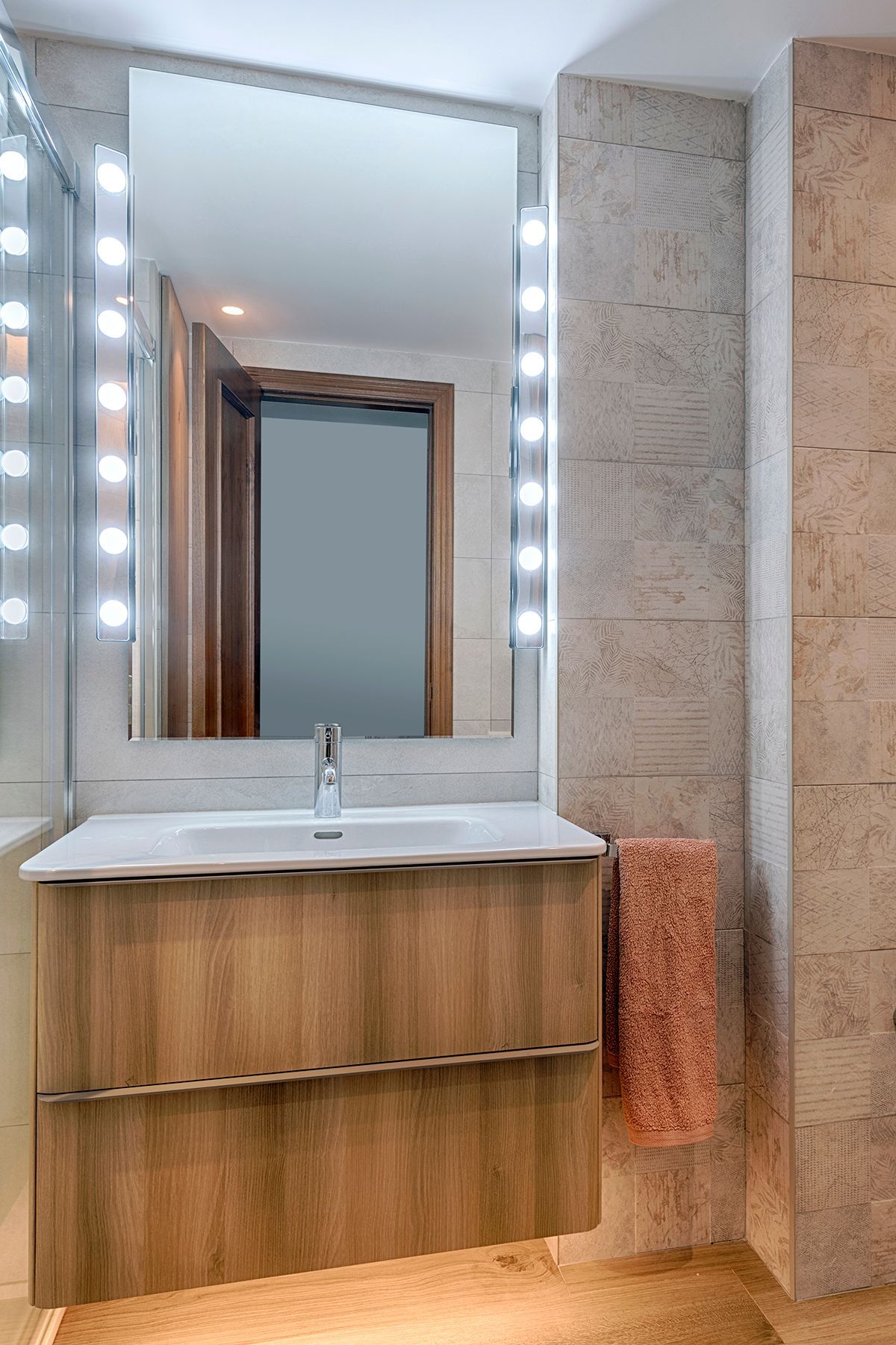 Un baño con lavabo, espejo y toallero.