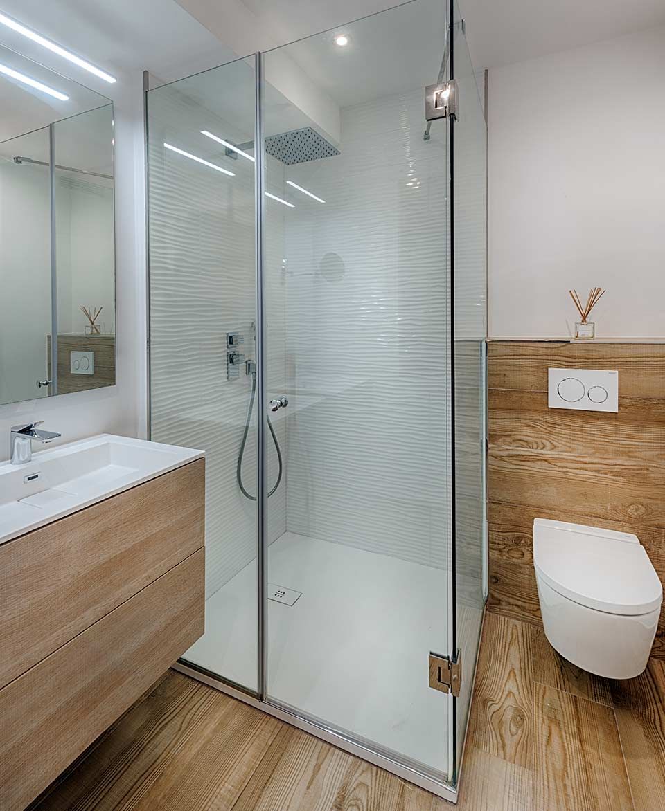 Un baño con ducha, lavabo, inodoro y espejo.