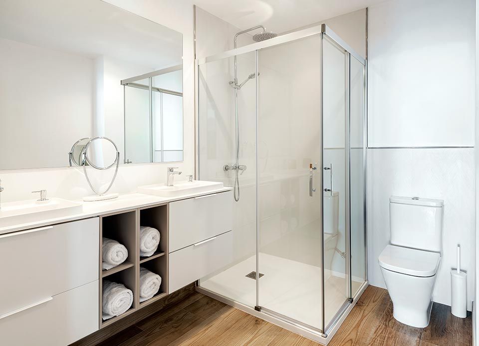 Un baño con inodoro, lavabo, ducha y espejo.