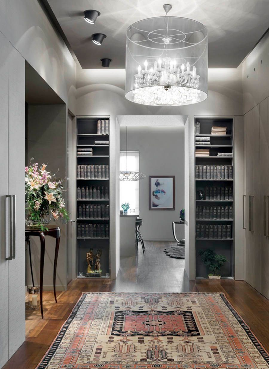 Un pasillo con una alfombra y una lámpara de araña colgando del techo.