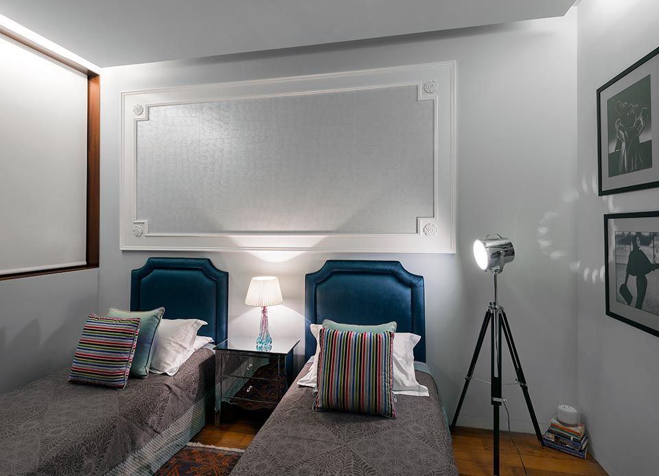 Un dormitorio con dos camas, una lámpara y un trípode.