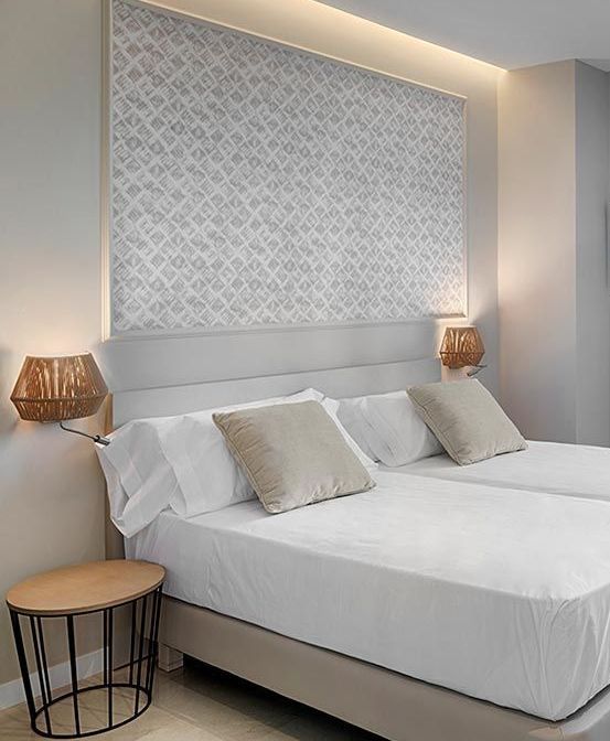 Un dormitorio con una cama, mesa y lámparas.