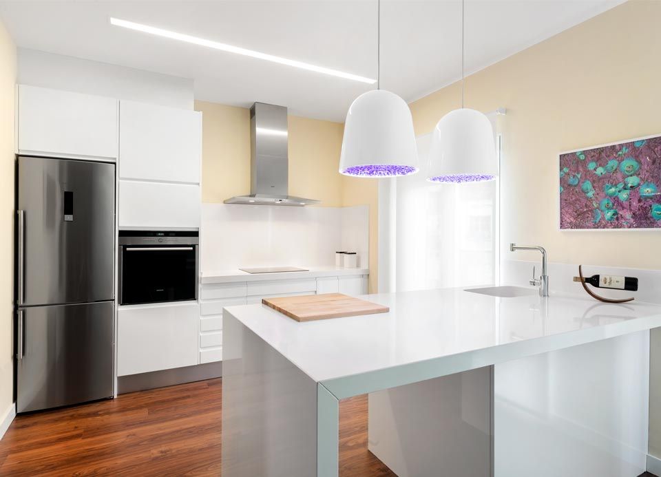 Una cocina con gabinetes blancos, electrodomésticos de acero inoxidable y una isla grande.