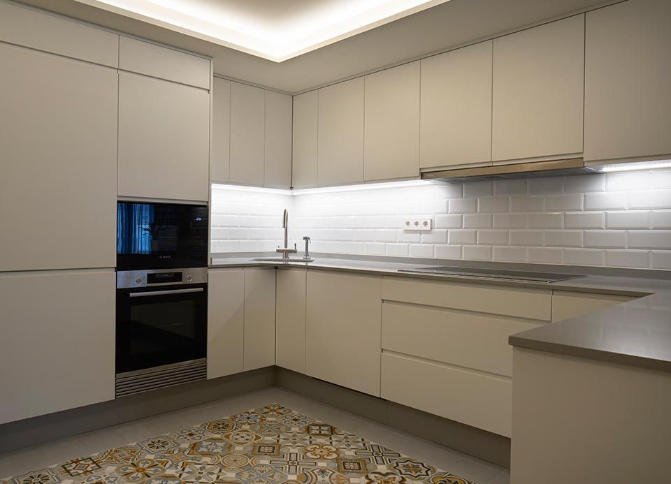 Una cocina con gabinetes blancos, electrodomésticos de acero inoxidable, un fregadero y un horno microondas.