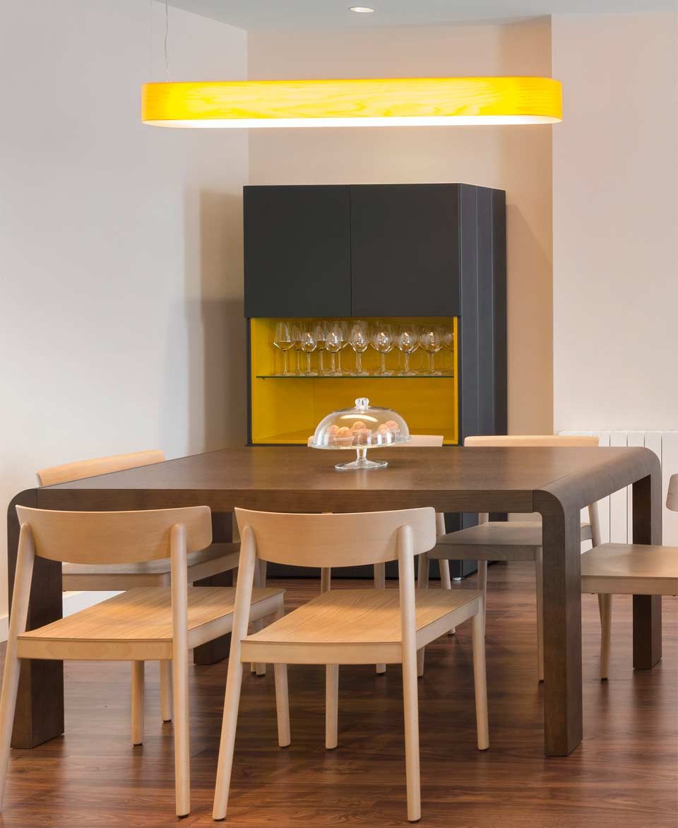 Una mesa de comedor y sillas con una luz amarilla colgando del techo.