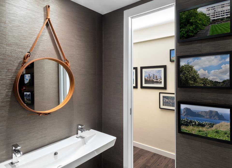 Un baño con lavabo, espejo y cuadros en la pared.