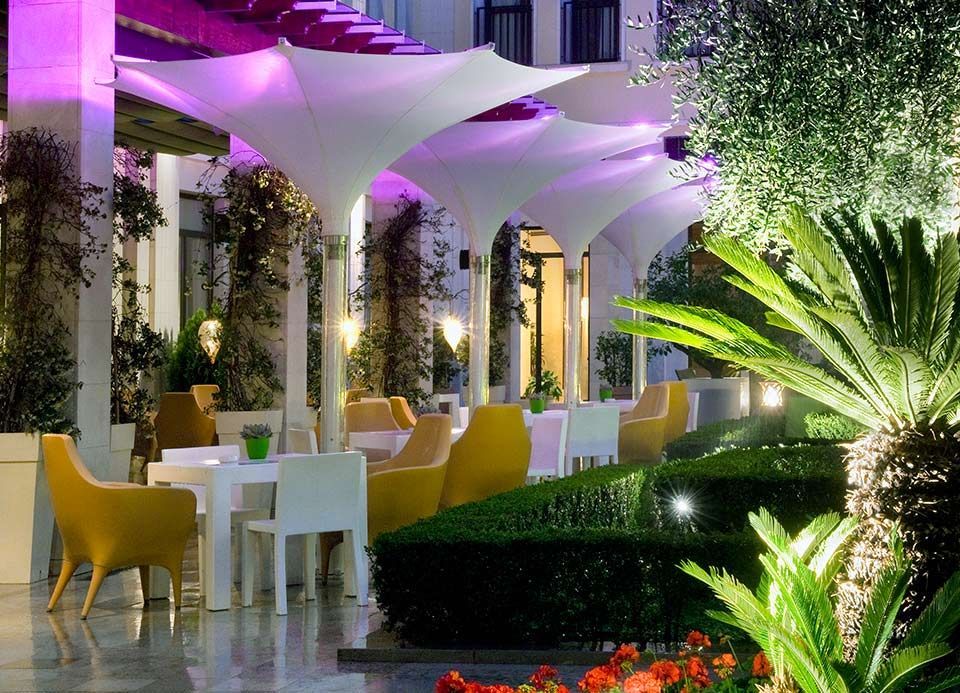 Un restaurante con mesas y sillas bajo sombrillas moradas.