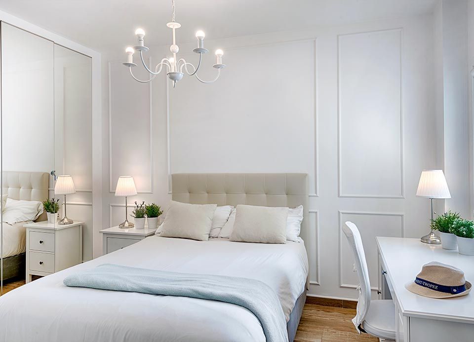 Un dormitorio con una cama, un escritorio, una mesita de noche y una lámpara de araña.