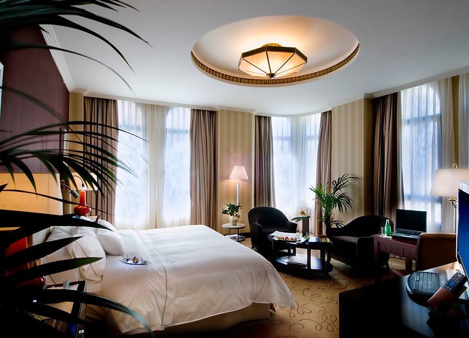 Una habitación de hotel con una cama grande y muchas ventanas.