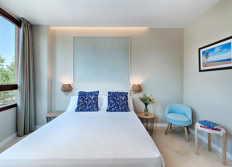 Una habitación de hotel con una cama, una silla, una mesa y una ventana.