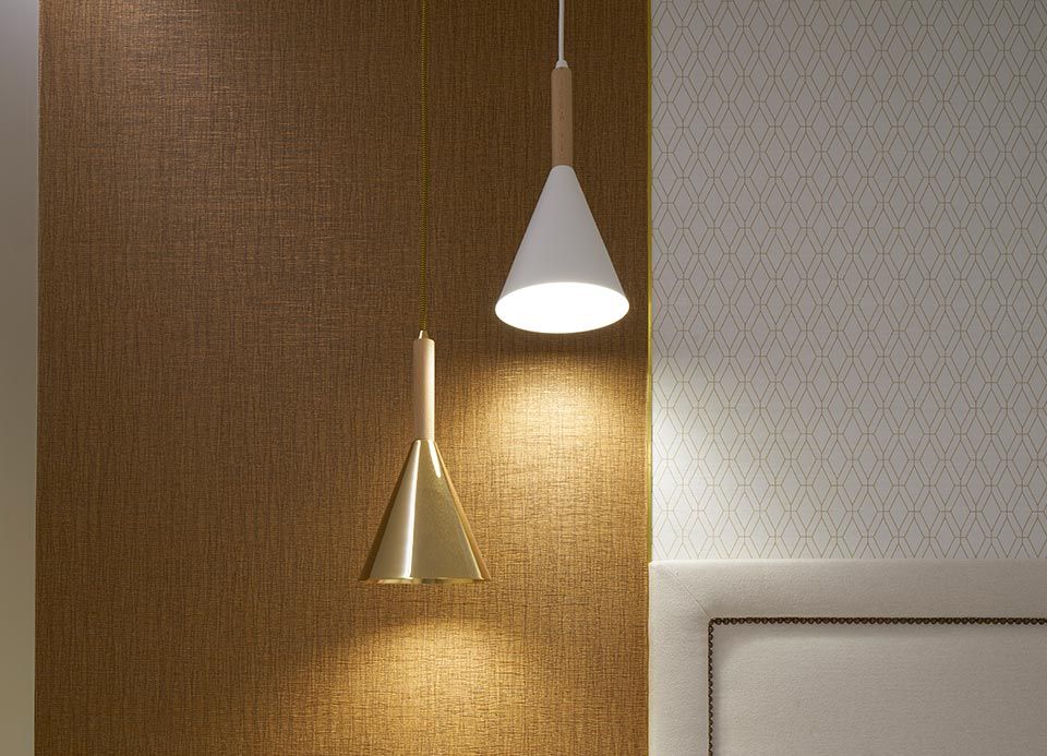 Dos lámparas colgantes cuelgan de una pared al lado de una cama.