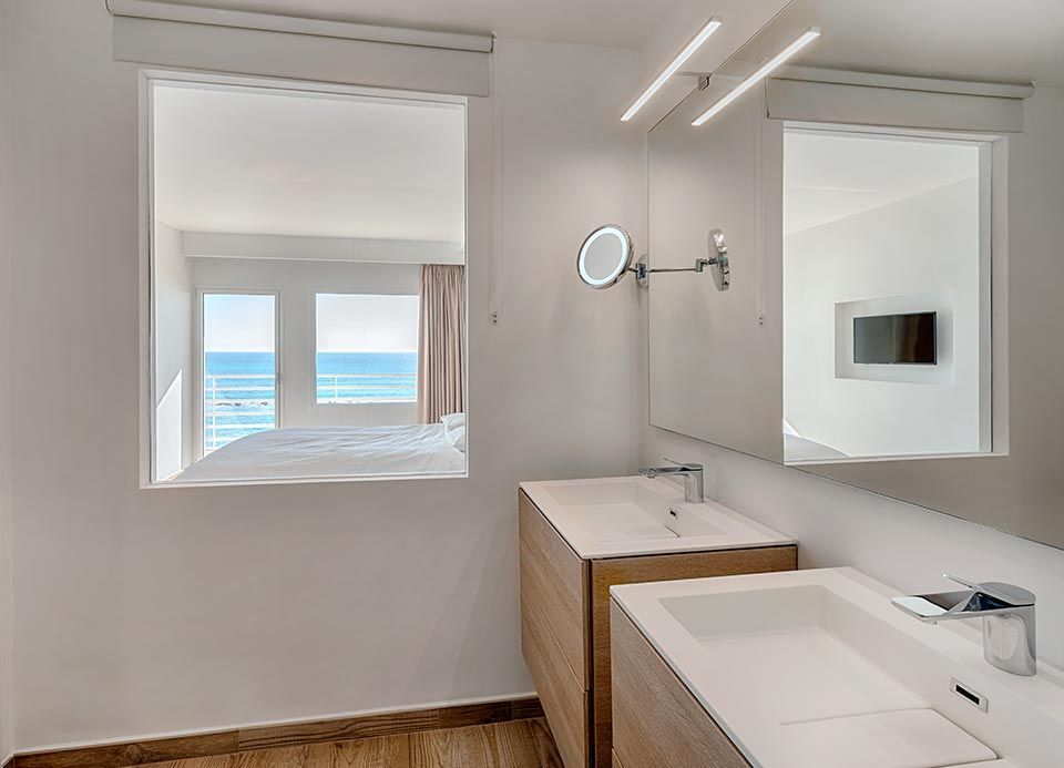 Un baño con dos lavabos y un espejo con vista al mar.