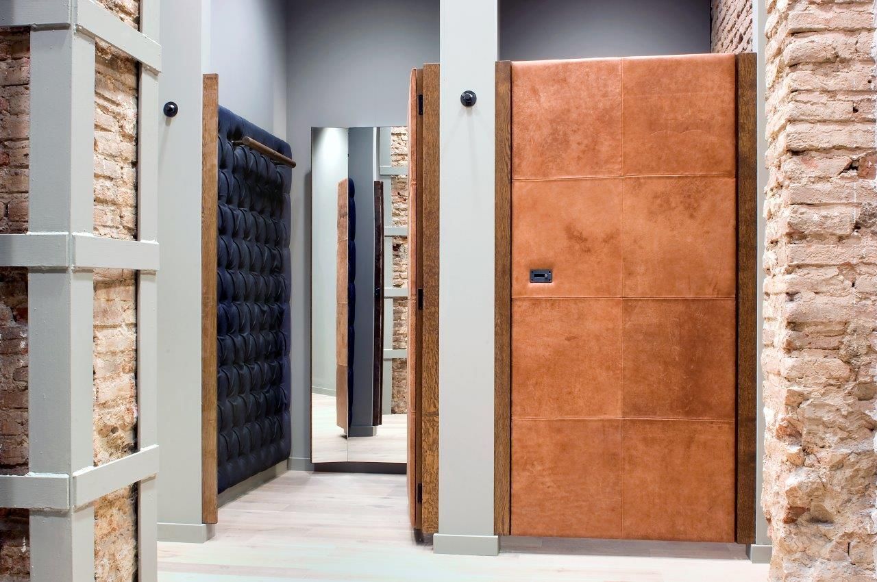 Un pasillo con una puerta marrón y un espejo.