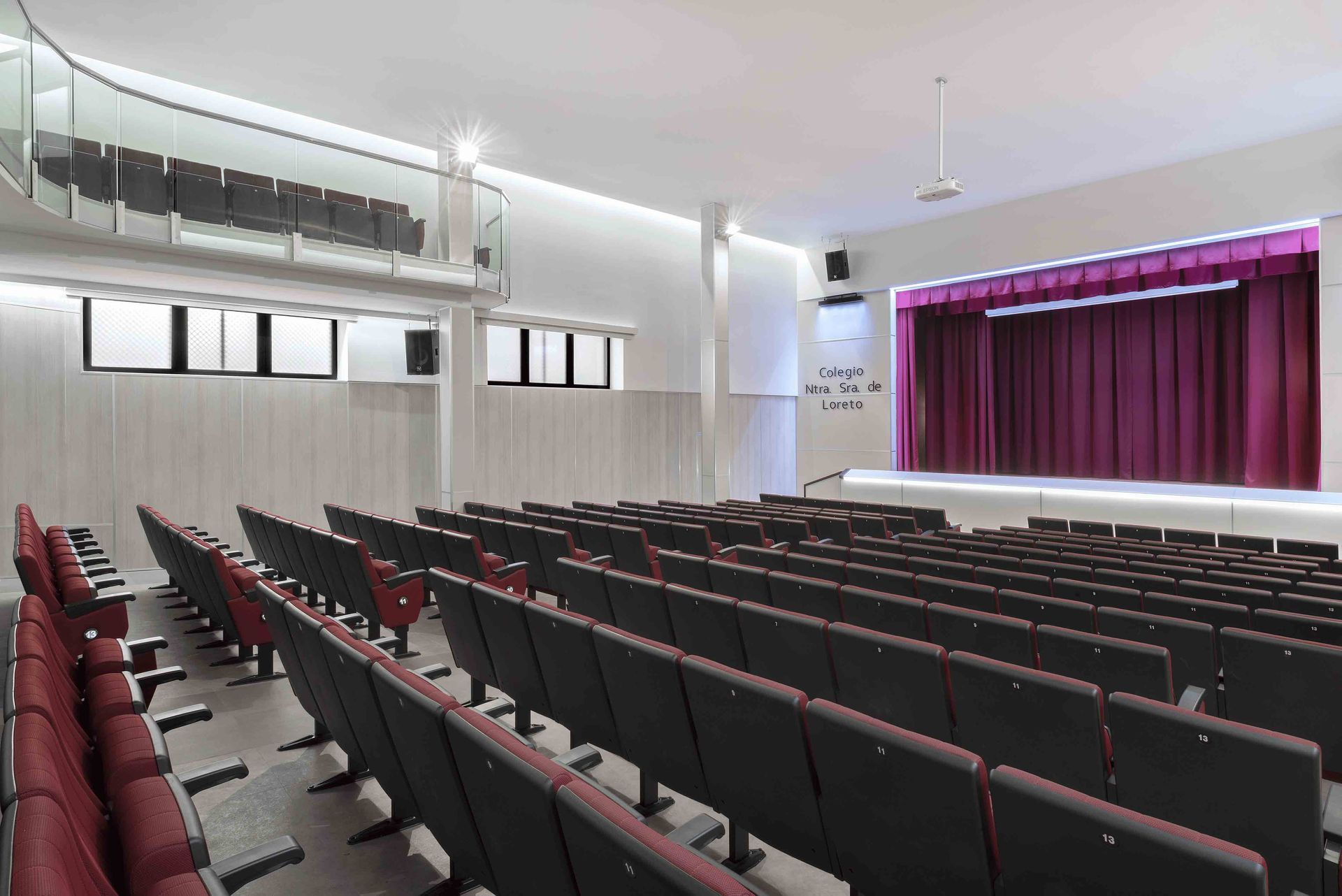 Un auditorio con filas de asientos y un escenario con una cortina morada.