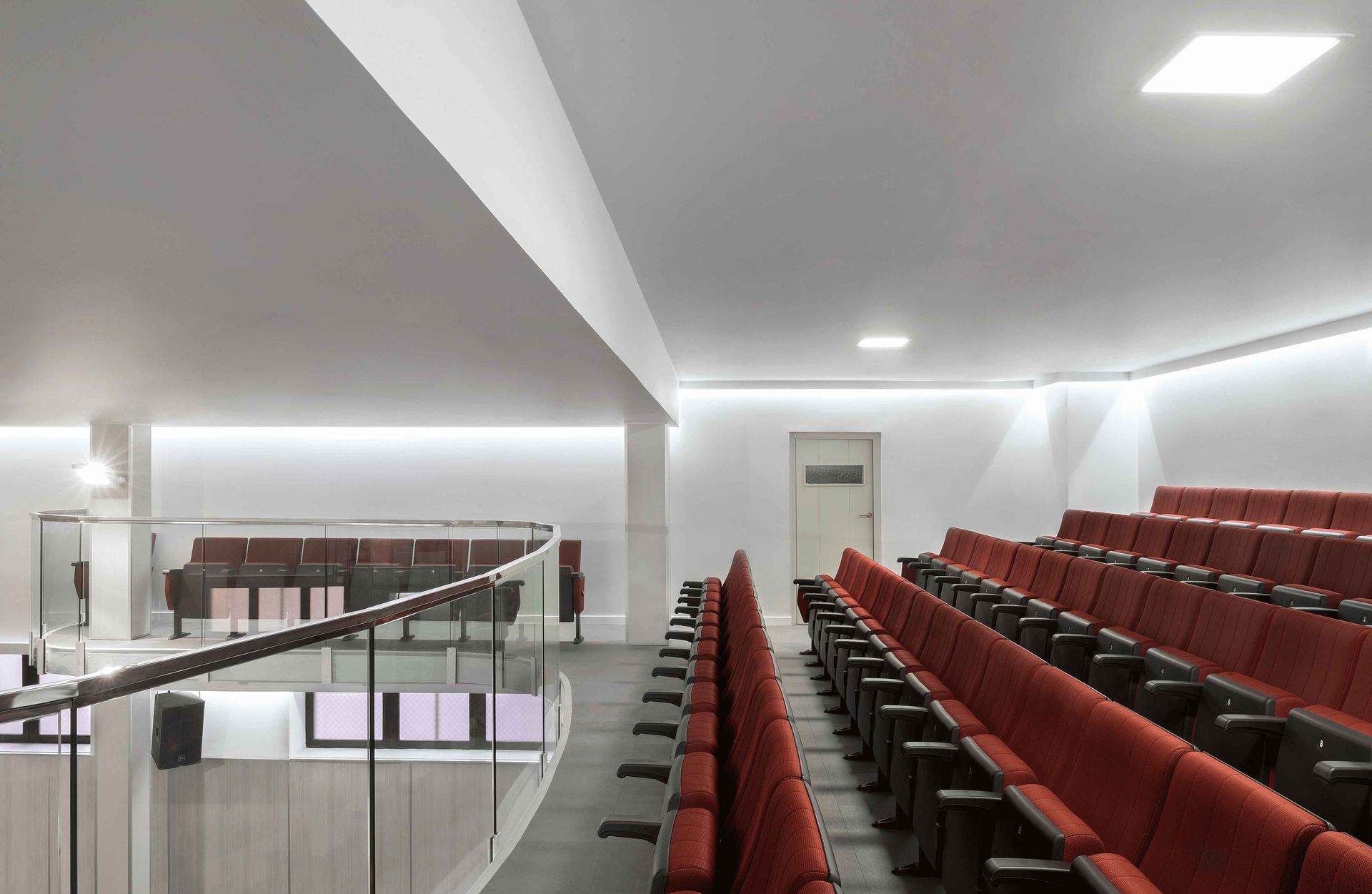 Un gran auditorio con asientos rojos y un balcón.