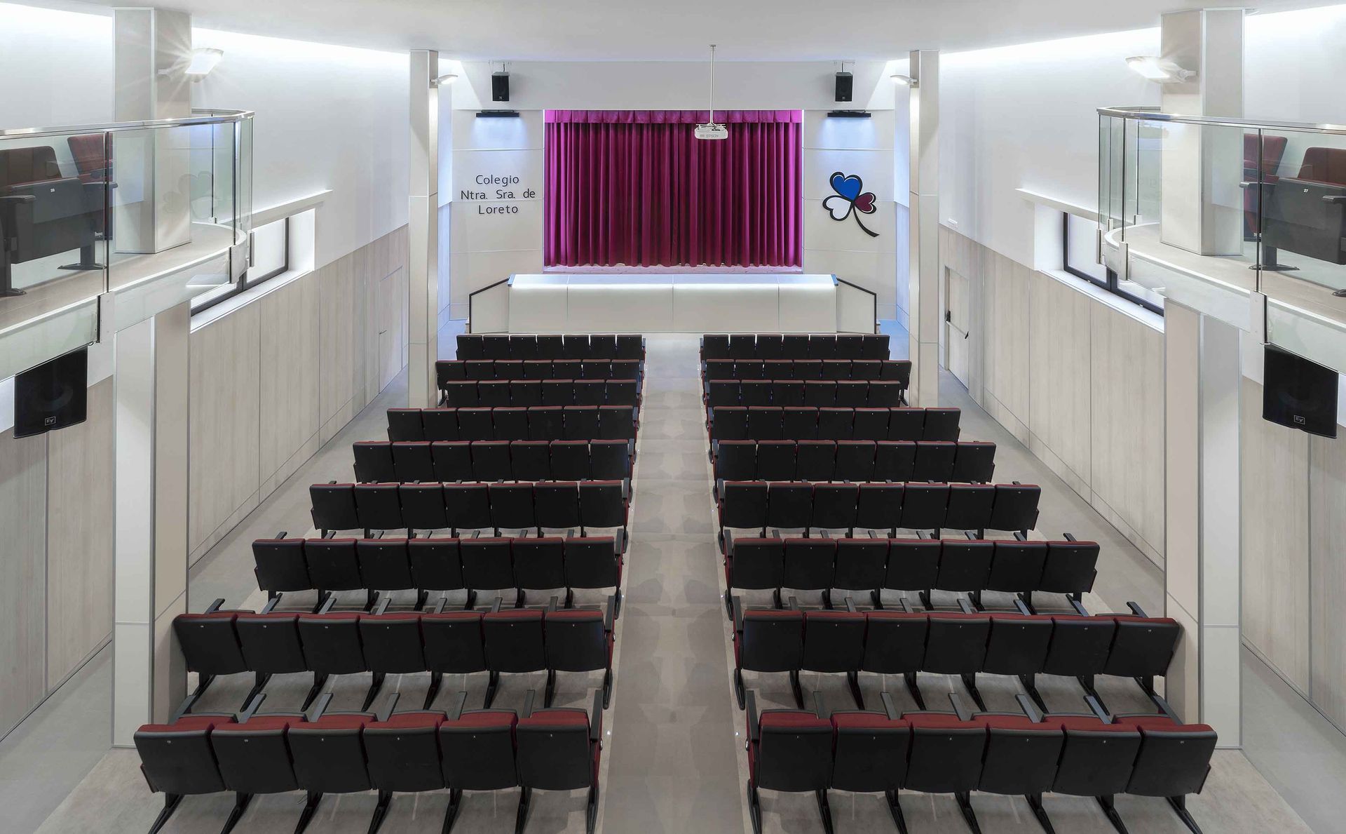 Un gran auditorio con filas de asientos y una cortina morada.