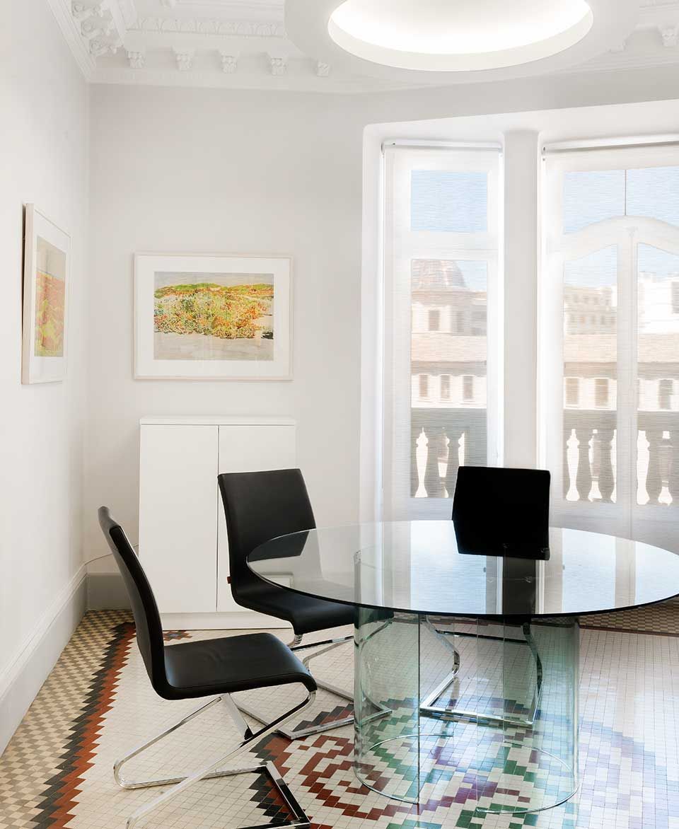 Un comedor con una mesa de cristal y sillas.