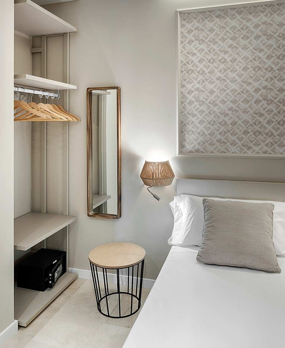 Un dormitorio con cama, mesa, espejo y armario.