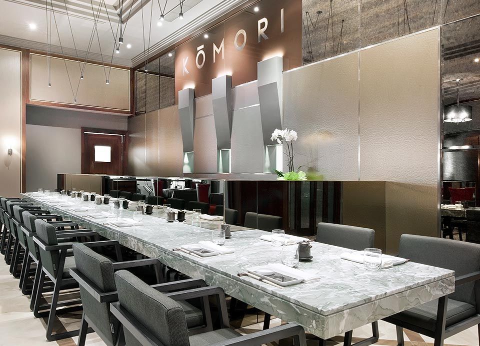 Una mesa larga con sillas en un restaurante con la palabra comori en la pared