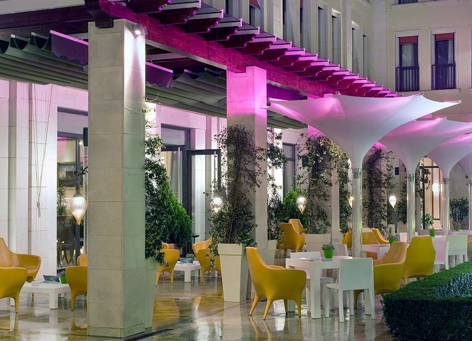 Un vestíbulo de hotel con mesas y sillas bajo un toldo rosa.